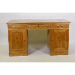 A C19th continental pine kneehole desk with three drawers and two cupboards, one fitted with three