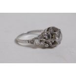 A platinum and diamond ring, set with a central stone, the pierced shoulders with three small