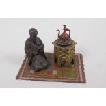 A cold painted bronze inkwell cast as an Arab gentleman kneeling on a rug, 14.5cm