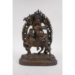 A Tibetan gilt bronze figure of a wrathful deity seated on horseback, double vajra mark to base,