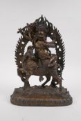 A Tibetan gilt bronze figure of a wrathful deity seated on horseback, double vajra mark to base,