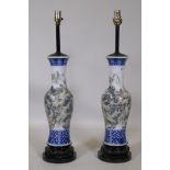 A pair of Chinese porcelain table lamps with famille verte decoration, mounted on carved wood