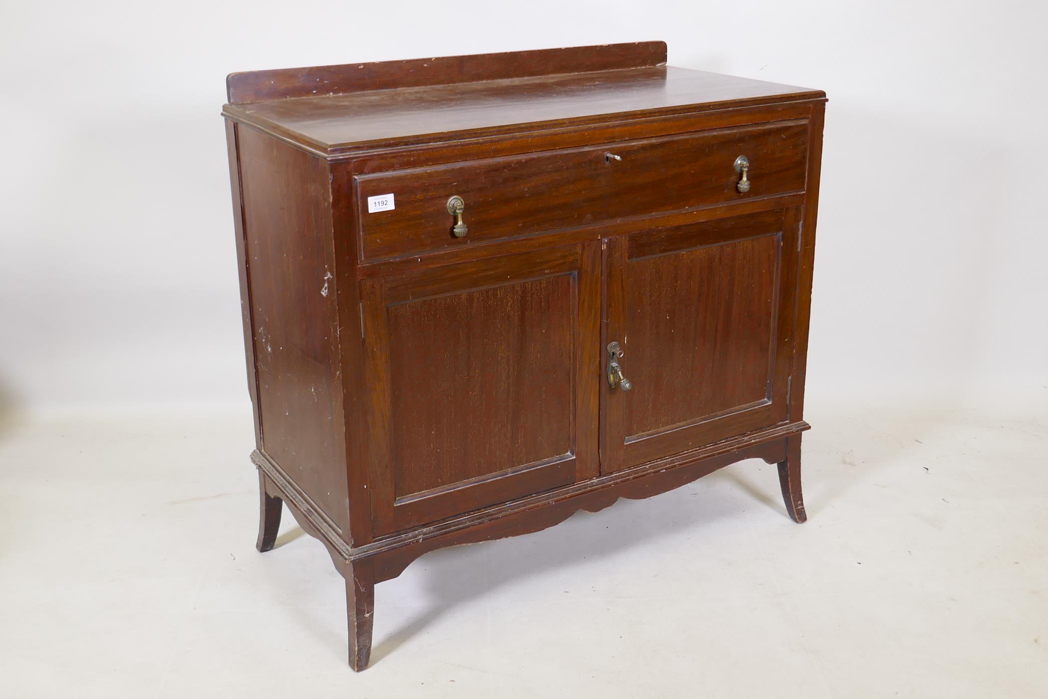 An Edwardian mahogany side cabinet with a single drawer over two cupboards, raised on swept