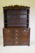 An oak dresser with delft rack over three drawers and two cupboards with arched fielded panels