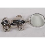 A desk top magnifying glass, the handle in the form of a silver plated racing car, 23cm long