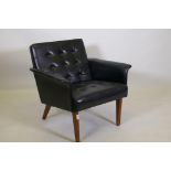 A mid century leatherette easy chair with button back and seat, raised on splay supports