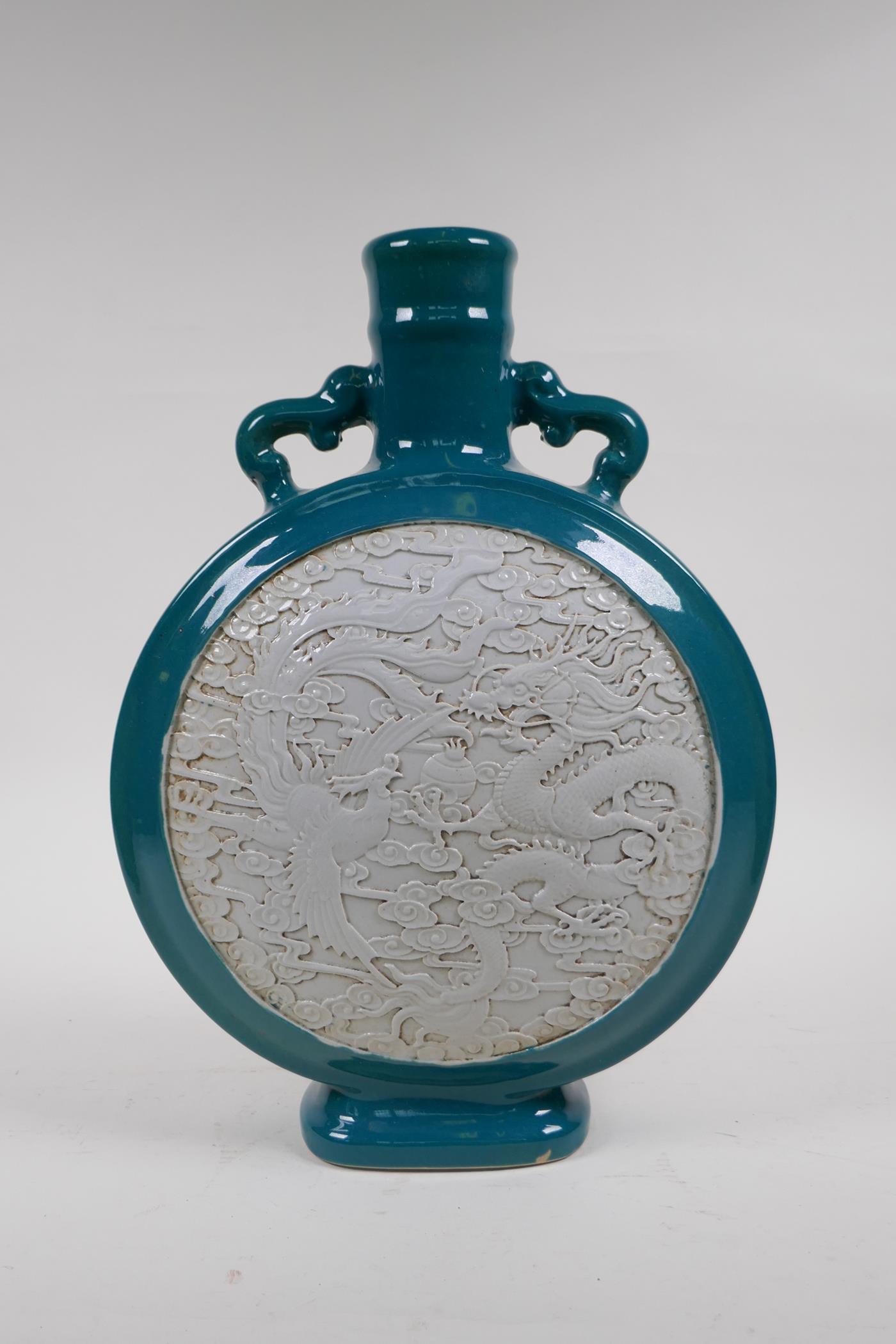 An emerald green glazed porcelain two handled moon flask with a white ground panel and raised dragon