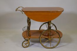 A vintage two tier hostess trolley with lacquered walnut tops, raised on brass columns and wheels,