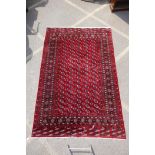 A deep red ground Persian Bokhara carpet, 184cm x 280cm