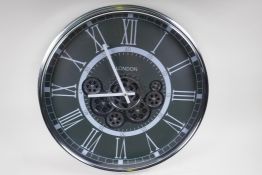 A wall clock with quartz movement and separately powered open cogwork, with white Roman numerals,