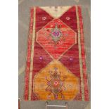 An Afghan rust ground full pile wool carpet with a tri-colour medallion design, 57" x 97"