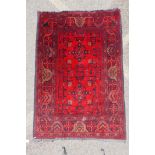 A Persian ruby red ground wool rug with traditional geometric design, 102cm x 148cm