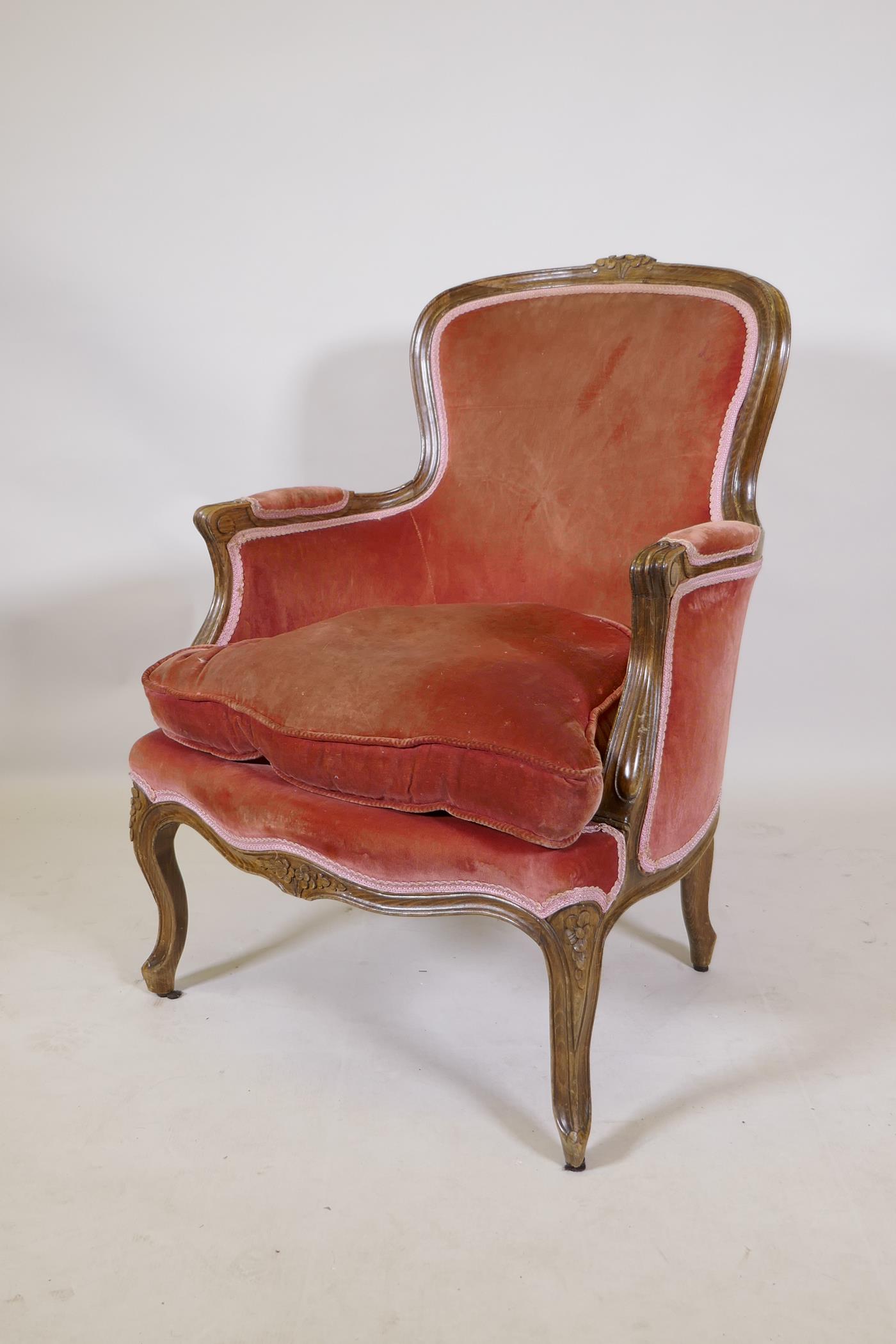 A French style beech wood arm chair, with carved decoration, raised on shaped supports