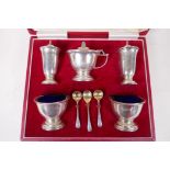 A cased hallmarked silver five piece cruet set, with three spoons and blue glass liners,
