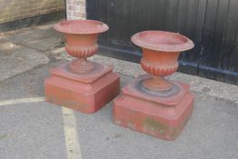A pair of large terracotta garden urns of classical form, on square plinth bases, 80cm high, 58cm