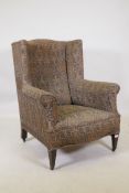 A Victorian wing back armchair, raised on mahogany square tapering supports with castors