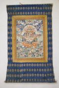 A C19th Tibetan hand painted Thangka with gilt highlights, mounted within a silk surround, image