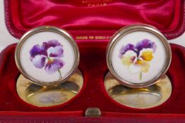 A pair of hallmarked silver menu holders with painted miniatures of flower heads, London 1905,