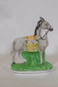 A C19th Staffordshire flat back figure of a donkey with panier, 19cm high