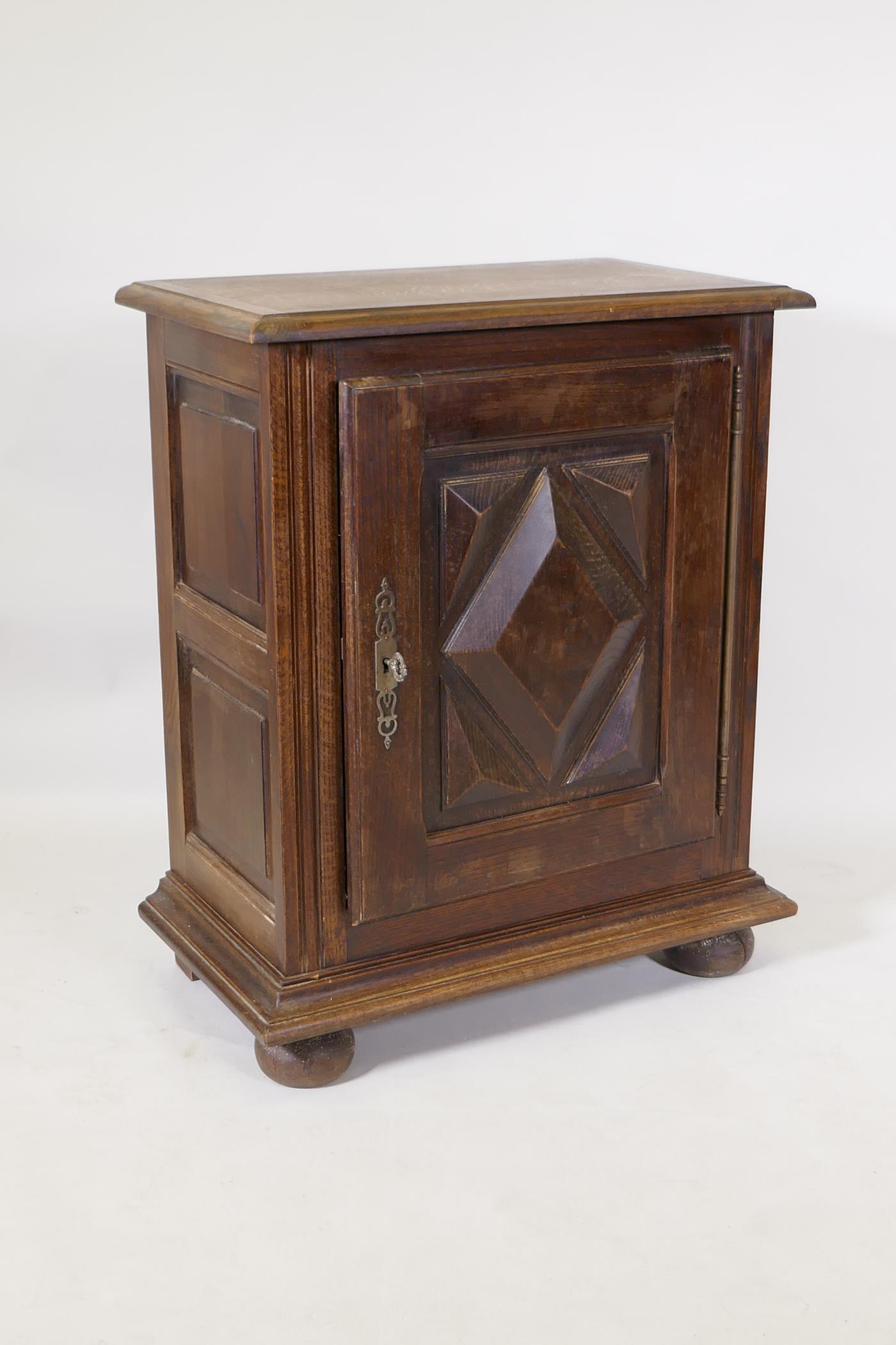 A French oak side cupboard, the single door with moulded decoration, raised on bun feet, 70 x 40 x