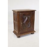 A French oak side cupboard, the single door with moulded decoration, raised on bun feet, 70 x 40 x