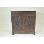 A C19th Anglo Indian padouk side cabinet with carved frieze and doors, raised on shaped supports,