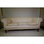 A Victorian Chesterfield settee with calico covers, raised on turned supports