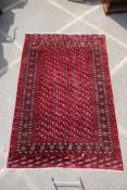 A deep red ground Persian Bokhara carpet, 184cm x 280cm
