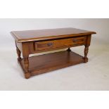 An oak two tier coffee table with cross banded top and single drawer, raised on turned supports, 100