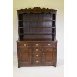 An oak dresser with delft rack over three drawers and two cupboards with arched fielded panels