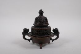 A Chinese bronze two handled censer and cover, with dragon knop and handles, raised on tripod