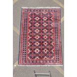 A Persian wool rug with Bokhara style medallion design and blue borders, 125cm x 180cm