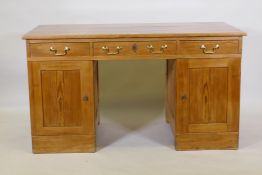 A C19th continental pine kneehole desk with three drawers and two cupboards, one fitted with three