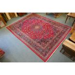 A large red ground Persian Kashen carpet with a fine woven multicolour medallion design, 300cm x
