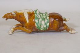 A Tang style ceramic figure of a leaping horse in green and ochre glaze, 32cm long