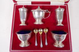 A cased hallmarked silver five piece cruet set, with three spoons and blue glass liners,