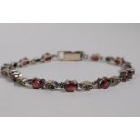 A 925 silver and garnet set line bracelet, 18cm long