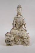 A Chinese blanc de chine porcelain figure of Quan Yin seated on a temple lion, impressed marks