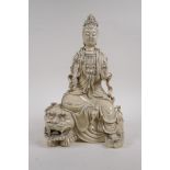 A Chinese blanc de chine porcelain figure of Quan Yin seated on a temple lion, impressed marks