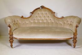 A Victorian carved walnut shaped back settee, with buttoned back and scrolled arms, 200 x 97cms