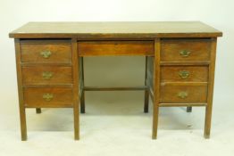 An oak office desk of five drawers, raised on square supports, early C20th, 138 x 62 x 77cms