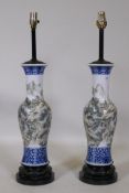 A pair of Chinese porcelain table lamps with famille verte decoration, mounted on carved wood