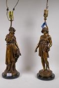 A pair of bronze table lamps in the form of classical figures, mounted on polished slate bases,