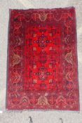 A Persian ruby red ground wool rug with traditional geometric design, 102cm x 148cm