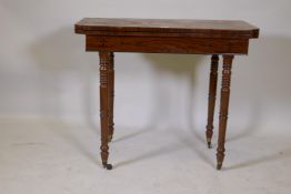 A C19th mahogany fold over tea table on ring turned supports and brass castors, 74 x 89 x 44cms