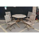 A teak garden table and four folding chairs