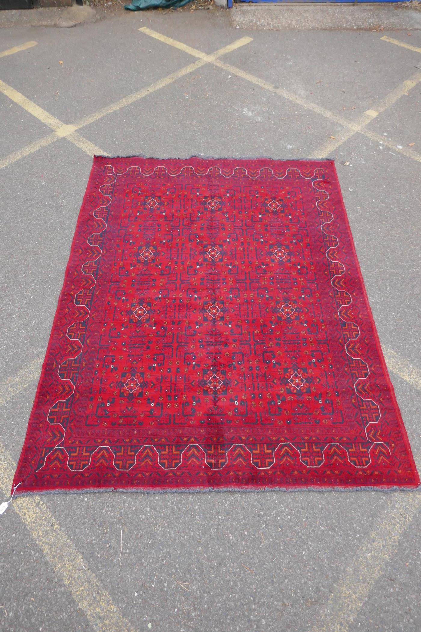 A Turkish deep red ground wool carpet with unique repeating floral geometric design, 165 x 230cms