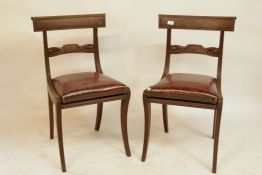 A pair of Regency mahogany side chairs with carved back rails and drop in leather seats