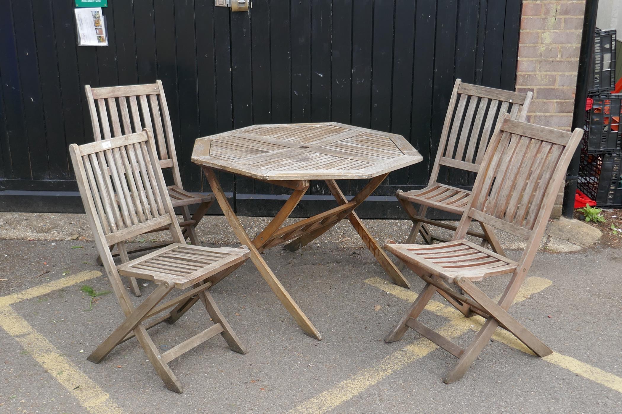 A teak garden table and four folding chairs