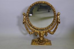 An antique giltwood and composition swing toilet mirror, AF losses, 63 x 70cms high